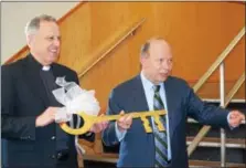  ?? MARIAN DENNIS – DIGITAL FIRST MEDIA ?? Monsignor Joseph Marino (left) and Jerry Parsons prepare to hand the key to the school over to its new owners. The school building at 844 Keim Street will be the new location for St. Aloysius Parish School, currently located at Beech and North Hanover...