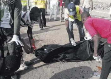  ?? JOSSY OLA/THE ASSOCIATED PRESS ?? People clear the scene after an explosion Saturday in Maiduguri, Nigeria. Twin explosions by female suicide bombers suspected to be with Boko Haram killed nine people and injured more than 20.