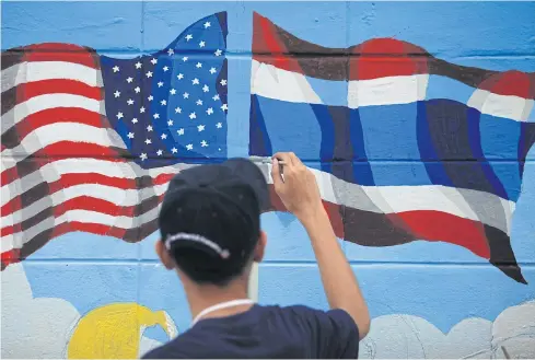  ?? PATIPAT JANTHONG ?? A student paints the national flags of Thailand and the United States on the wall of the US Embassy. The Thai-US alliance has underperfo­rmed as Thailand is stuck in a domestic holding pattern.