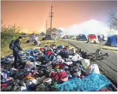  ??  ?? Far from flames: Evacuees sifting through a pile of clothing at a makeshift shelter in a Walmart parking lot in Chico, California. — AFP