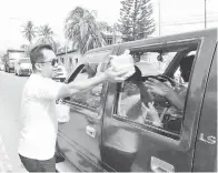  ??  ?? JAMAWI mengagih-agihkan bubur lambuk kepada para pemandu kenderaan.