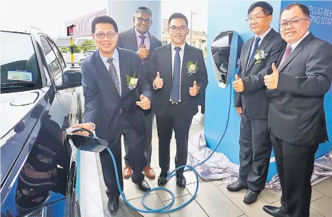  ?? — Photo by Muhammad Rais Sanusi ?? Julaihi (left) gives his thumbs-up while he charges a BMW hybrid car. With him from right are Stephen, Tay, Jonathan and Sashi.