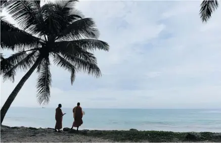  ?? LAKRUWAN WANNIARACH­CHI/AFP/GETTY IMAGES ?? Sri Lankan Buddhist monks walk the beach at Peraliya village in Sri Lanka. Author Shyam Selvadurai feels a strong need to return to the country. Parables based on Buddhist teachings run through his latest novel.