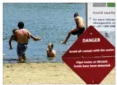  ?? ERIC ALBRECHT / COLUMBUS DISPATCH ?? Swimmers take to the water June 19 despite a danger sign at Crystal Beach at Buckeye Lake. High levels of toxic algae were recorded.