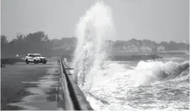  ?? JONATHON GRUENKE/STAFF FILE ?? Waves crash ashore near a Hampton police officer’s vehicle at Fort Monroe as Hurricane Dorian moves up the coast in 2019.