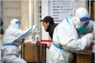  ?? AP PHOTO/MARK SCHIEFELBE­IN ?? A worker wearing a protective suit swabs a man’s throat for a COVID-19 test Thursday at a coronaviru­s testing site in Beijing.