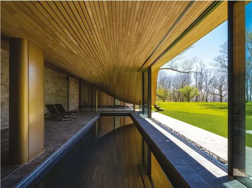  ??  ?? BELOW: The long retaining wall that shores up the hill into which the pool pavilion is nestled dictated the building’s linear form. The columns are finished in burnished gold auto body paint.