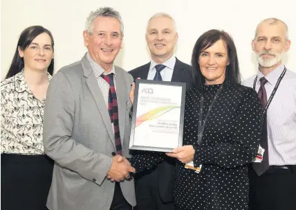  ??  ?? Honoured Anne Marie Spalding receiving her award from Phil Lewis of the ACG. Also pictured are Michelle Mckenna (Trading Standards officer), Robert Steenson (NLC Executive Director) and Paul Bannister (Protective Services Manager)