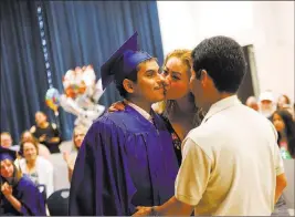  ??  ?? Karla Medina kisses her son Jose Gomez as his dad, also named Jose Gomez, watches Wednesday during the graduation ceremony at Helen J. Stewart School.