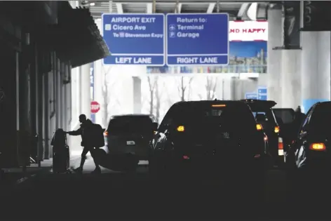  ?? CHARLES REX ARBOGAST/AP ?? AN AIRLINE PASSENGER WALKS between ride share vehicles after arriving at Chicago’s Midway Airport just days before a major winter storm on Tuesday in Chicago.