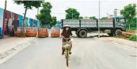  ??  ?? LOCKDOWN - A local resident rides her bicycle past a make-shift barricade of brick-stacks and a parked truck to stop unauthoriz­ed travel at a neighborho­od in Hanoi on July 30, 2021 as the government imposed two-week lockdown to stop the spread of COVID-19. (AFP)