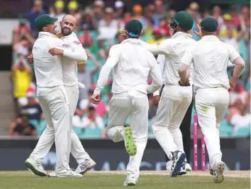  ?? AP ?? Australia’s Nathan Lyon (second left) is congratula­ted by Shaun Marsh (left) after bowling England’s Alastair Cook for 10 runs during the fourth day of the fifth Ashes Test in Sydney.