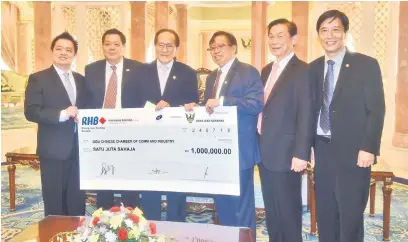  ??  ?? DANA: Hii (tiga kiri) bersama ahli SCCCI lain menerima replika cek bernilai RM1 juta daripada Abang Johari di Kuching, semalam.