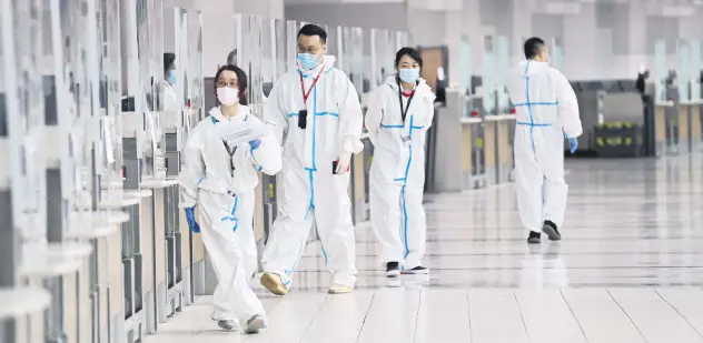  ??  ?? Workers walk by a check-in counter at Pearson Internatio­nal Airport during the COVID-19 pandemic, Toronto, Canada, Oct. 14, 2020.