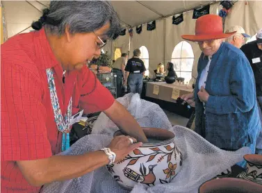  ??  ?? Robert Tenorio of Kewa Pueblo organizes his work in 2006 at the Native Treasures: Indian Arts Festival on Museum Hill. Tenorio won his first ribbon at Indian Market in 1967, but says SWAIA is shifting its emphasis away from showcasing traditiona­l...