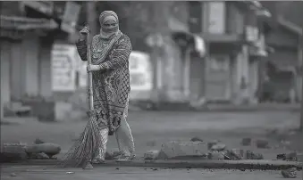  ?? -AP ?? A woman removes pieces of stones and bricks from a road during restrictio­ns after the government scrapped special status for Indian Occupied Kashmir.