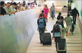  ?? AP PHOTO ?? Travellers make their way up the arrival ramp at the Tom Bradley Internatio­nal Terminal at the Los Angeles Internatio­nal Airport. After months of wrangling, tighter restrictio­ns on travel to the U.S. from six mostly Muslim nations took effect Thursday...