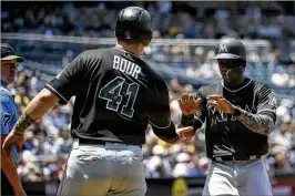  ?? DENIS POROY/GETTY IMAGES ?? Miami’s Cameron Maybin is congratula­ted by Justin Bour after scoring during the first inning Monday against the Padres in San Diego.