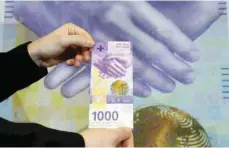  ?? — Reuters ?? An employee of Swiss National Bank presents the new 1,000-franc banknote in Zurich.