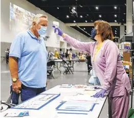  ?? EDUARDO CONTRERAS U-T ?? Cindy Marshall, who normally works at the San Diego Public Library, takes the temperatur­e of Richard Nichols, who is a resident at the homeless shelter at the San Diego Convention Center in downtown.