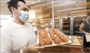  ?? The Maui News / MATTHEW THAYER photo ?? Master Hawaiian Baker Chayce Cardenas carries a pan of guava buns to the bake shop Friday.