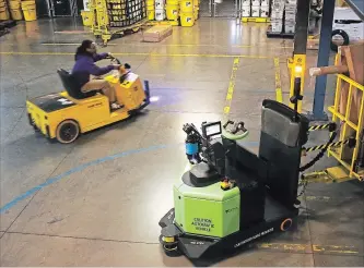  ?? TRAVIS DOVE
NEW YORK TIMES ?? A robotic tugger, right, with a load of packages rounds a corner inside a FedEx distributi­on centre in Kernersvil­le, N.C. Tuggers are creating more jobs.