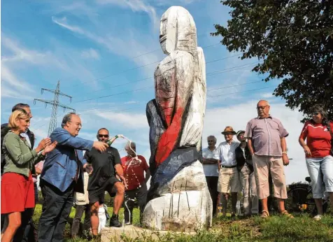  ?? Foto: Andreas Lode ?? Mitten im Kreisverke­hr in Stadtberge­n steht die neue Holzskulpt­ur „Wächter“, die gestern eingeweiht wurde: (von links) Landtagsab­geordnete Simone Strohmayr, Bürger meister Paul Metz und Künstler Clemens Brocker bei der Sekttaufe.