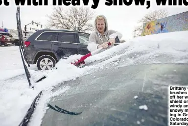  ?? AP ?? Brittany Culp brushes snow off her windshield on a windy and snowy morning in Greeley, Colorado on Saturday.