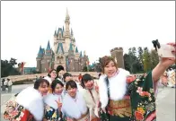  ?? KYODO NEWS VIA GETTY IMAGES ?? Japanese women in kimonos take a selfie at Tokyo Disneyland during a ceremony marking their coming of age on Monday.