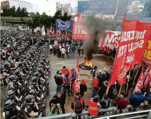  ?? Jorge Saenz/ap ?? Policiais fazem barreira contra grevistas que queimaram pneus ontem em Buenos Aires; central sindical estima que mais de um milhão aderiram à greve