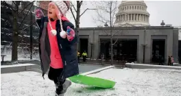  ?? — AP ?? Charlotte Simpson of Washington laughs in the snow as she sleds on a small hill by the Capitol Visitors Center on Capitol Hill in Washington on Thursday.