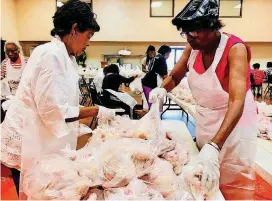  ?? [PHOTOS BY CARLA HINTON, THE OKLAHOMAN] ?? Fairview Baptist Church members Shirley Townsend and Jean Fisher place chickens into bags to be distribute­d as part of the National Baptist Convention’s food giveaway Friday at the church, 1700 NE 7.