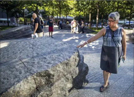  ?? AP PHOTO/MARY ALTAFFER ?? A visitor touches one of the granite slabs at the 9/11 Memorial Glade at the National September 11 Memorial & Museum in New York.