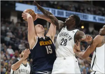  ?? DAVID ZALUBOWSKI — THE ASSOCIATED PRESS ?? Denver Nuggets center Nikola Jokic, second from left, drives the basket past, from left to right, Brooklyn Nets guard Seth Curry, forward Dorian Finney-smith and center Nic Claxton in the second half of an NBA basketball game Sunday in Denver.