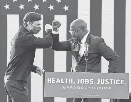  ?? JESSICA MCGOWAN/ GETTY IMAGES ?? New Georgia Democratic Senators- elect Jon Ossoff, left, and Raphael Warnock headline a drive- in voting rally as candidates last month in Stonecrest, Ga.