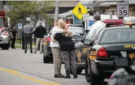  ?? Tom Dodge / The Columbus Dispatch via Associated Press ?? People hug outside Pine Kirk Care Center in Kirkersvil­le, Ohio, on Friday. Authoritie­s say Kirkersvil­le Police Chief Steven Eric Disario and two nursing home employees were killed by a gunman who was later found dead inside.