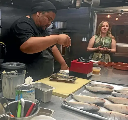  ?? JOANNE BUTCHER ?? Fillipino-American chef Alvin Cailan seasons the fish as Hillary Eaton speaks to the group.