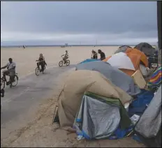  ?? JAE C. HONG/AP PHOTO ?? People ride their bikes past a homeless encampment set up along the boardwalk in the Venice neighborho­od of Los Angeles. The share of Americans living in poverty rose slightly as the COVID pandemic shook the economy last year, but massive relief payments pumped out by Congress eased hardship for many, the Census Bureau reported Tuesday.