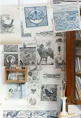  ??  ?? Right: The walls of Lou’s studio are lined with her prints. On her wooden work desk sits a bookcase full of reference books she uses for her work