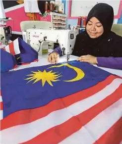  ??  ?? AMIRA menjahit busana yang bertemakan Jalur Gemilang untuk sambutan Hari Kemerdekaa­n yang ke 62.