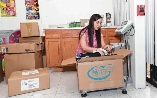  ?? Fotos de Juan DeLeón ?? Giuliana Donoso, empleada de la empresa Colombian Cargo, revisa una caja con ropa para niños antes de enviarla a Colombia para la Navidad.