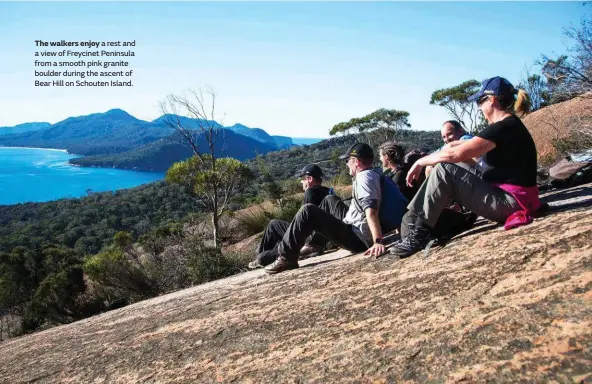  ??  ?? The walkers enjoy a rest and a view of Freycinet Peninsula from a smooth pink granite boulder during the ascent of Bear Hill on Schouten Island.