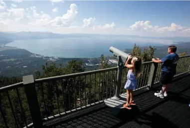  ?? ASSOCIATED PRESS ?? In this Aug. 8, 2017, file photo, Lilyana Allen, of Guam, uses a telescope to view Lake Tahoe from an observatio­n platform at the Heavenly Mountain Resort during a family visit to South Lake Tahoe, Calif. A new report on the progress of efforts to protect Lake Tahoe says removing an invasive shrimp from the mountain waters could offset a decline in clarity and other damage from human-caused global warming.