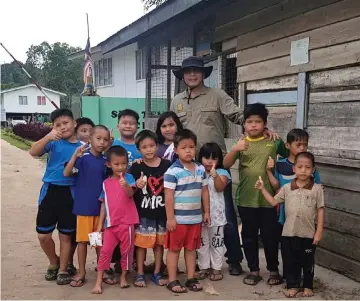  ??  ?? Dennis poses with a group of children at Long San.