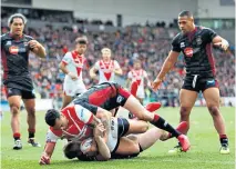  ??  ?? It’s a squeeze: Zeb Taia (red and white) scores St Helens’ second try despite the attentions of Wigan players