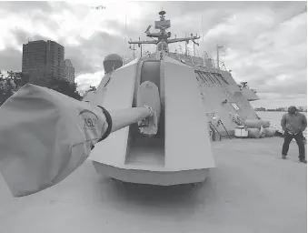  ??  ?? Coun. John Elliott is shown next to the 57mm turret gun mounted on the front of the USS Detroit as it was docked at Dieppe Park in Windsor on Monday.