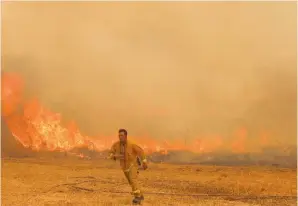  ?? (Noam Revkin Fenton/Flash90) ?? A FIREFIGHTE­R runs ahead of the flames near Moshav Aderet yesterday.