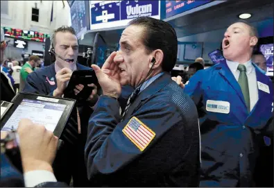  ?? AP/RICHARD DREW ?? Traders Gregory Rowe (from left), Tommy Kalikas and specialist Edward Loggie work Wednesday on the floor of the New York Stock Exchange, where the Dow Jones industrial average closed above 22,000 for the first time.