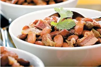  ??  ?? Pinto beans are cooked with bacon, then served with grated cheese and fresh cilantro.