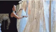  ?? MIKE DE SISTI / MILWAUKEE JOURNAL SENTINEL ?? Christina Alexander Wegner straighten­s bridal gowns at her second store, White Dress Off the Rack.